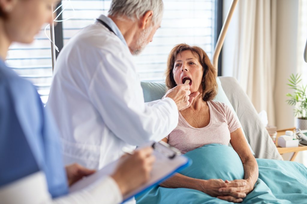 Senior male doctor examining a woman patient in hospital.